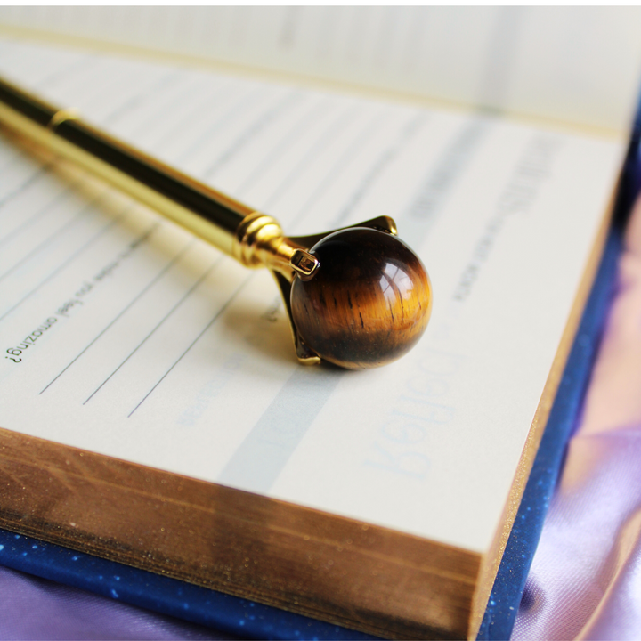 Crystal pen for mental clarity with Tigers Eye crystal ball on top of journals