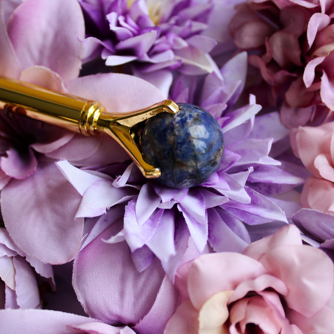 Sodalite crystal pen lying on purple flowers