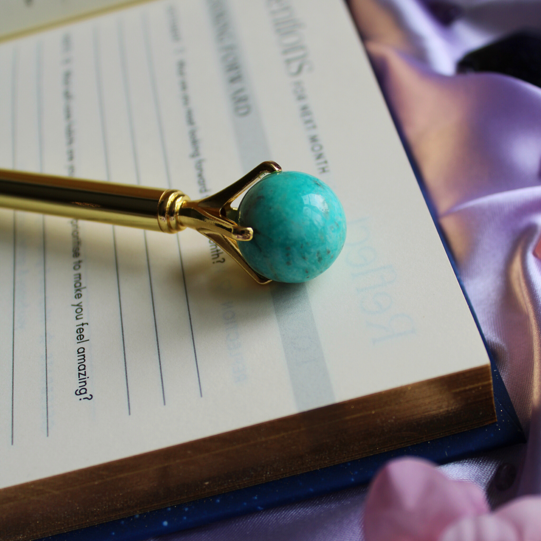 Amazonite crystal pen to create harmony & balance lying on a gratitude journal