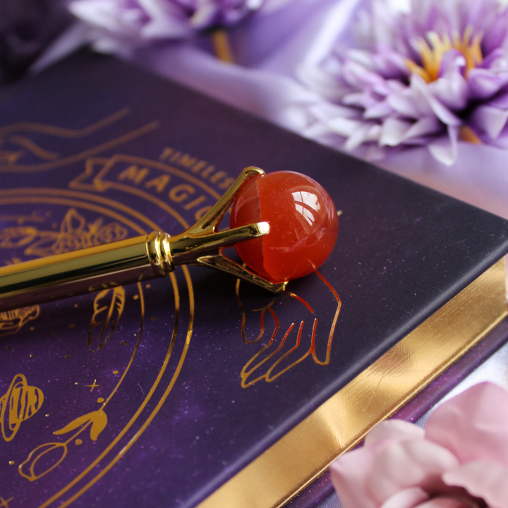 Carnelian crystal pen for self esteem resting on a manifestation journal
