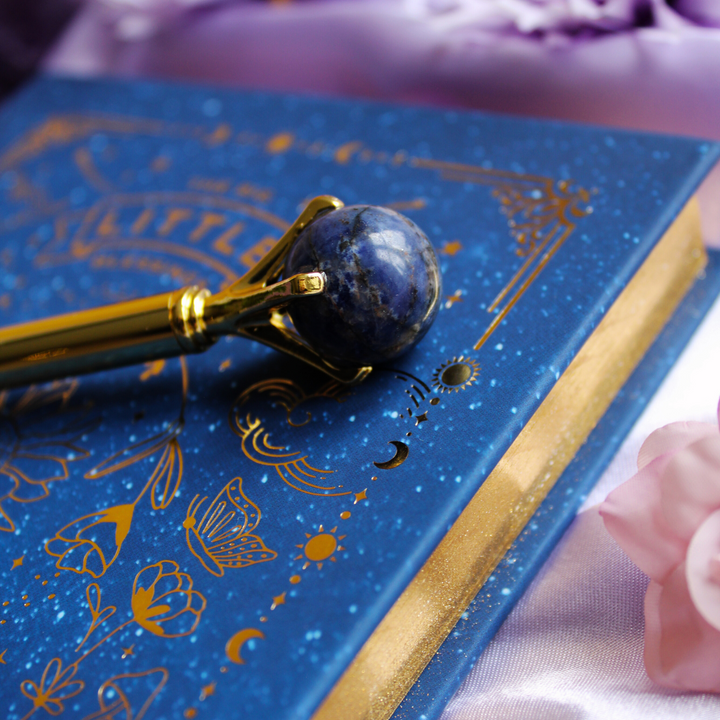 Sodalite pen on top of a blue & gold celestial gratitude journal