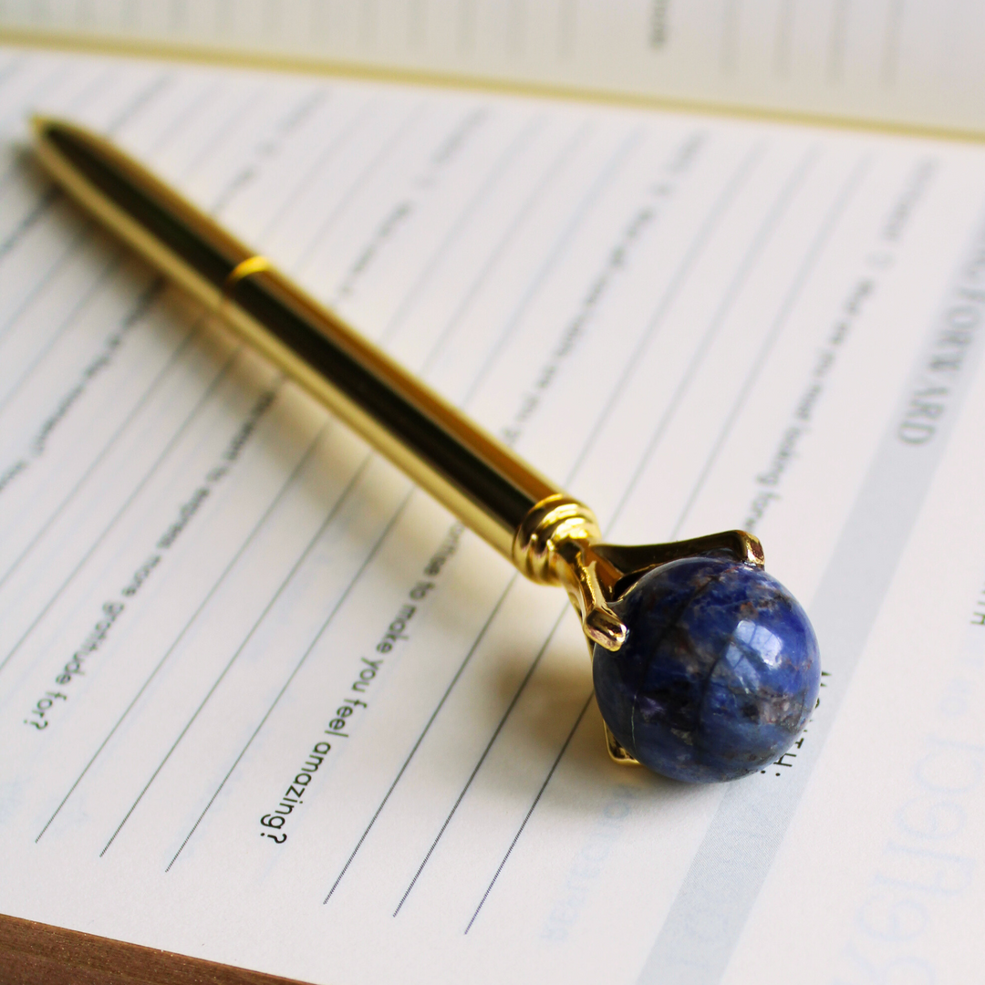 Sodalite crystal pen for intuition on top of an open spiritual journal