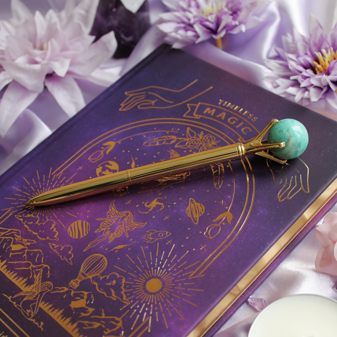 Amazonite crystal pen to create harmony & balance lying on a manifestation journal