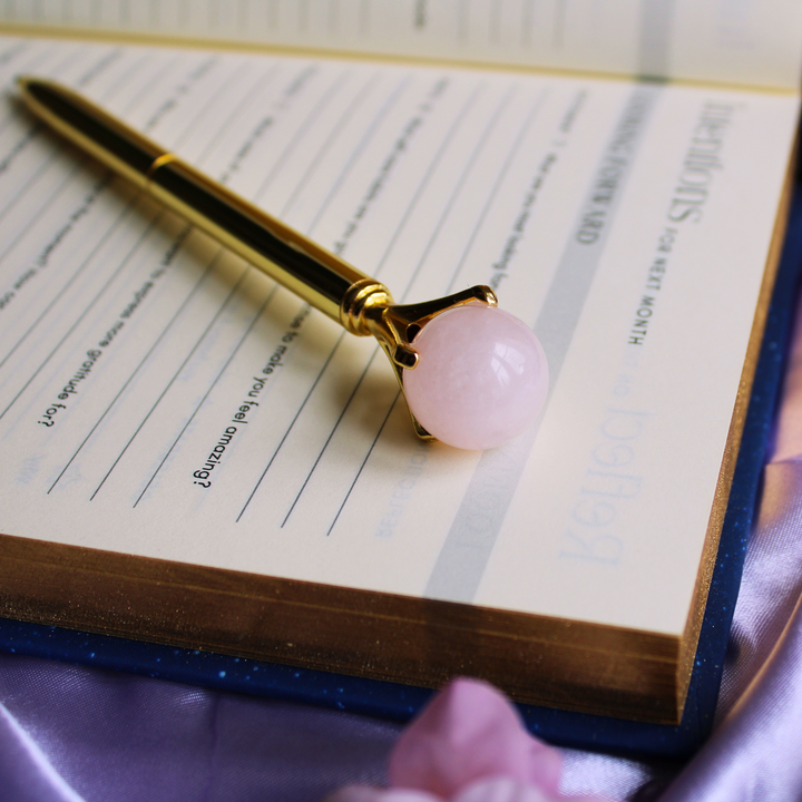 Rose Quartz Crystal ball pen for opening the heart chakra on top of a guided gratitude journal