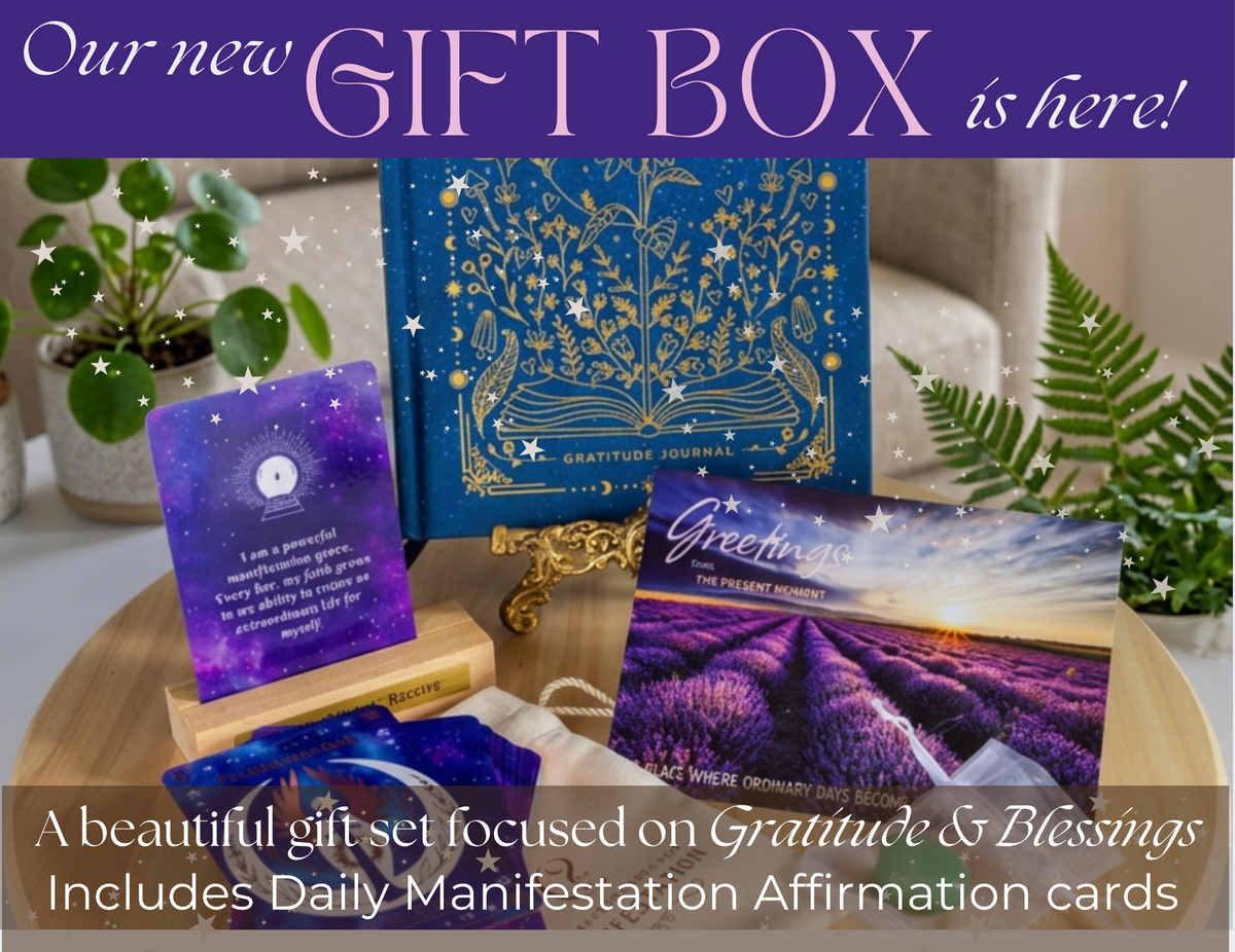 A gift set displayed on a wooden tray, featuring a blue book with gold ornamental illustrations, purple affirmation cards, a lavender field card GIFT SET