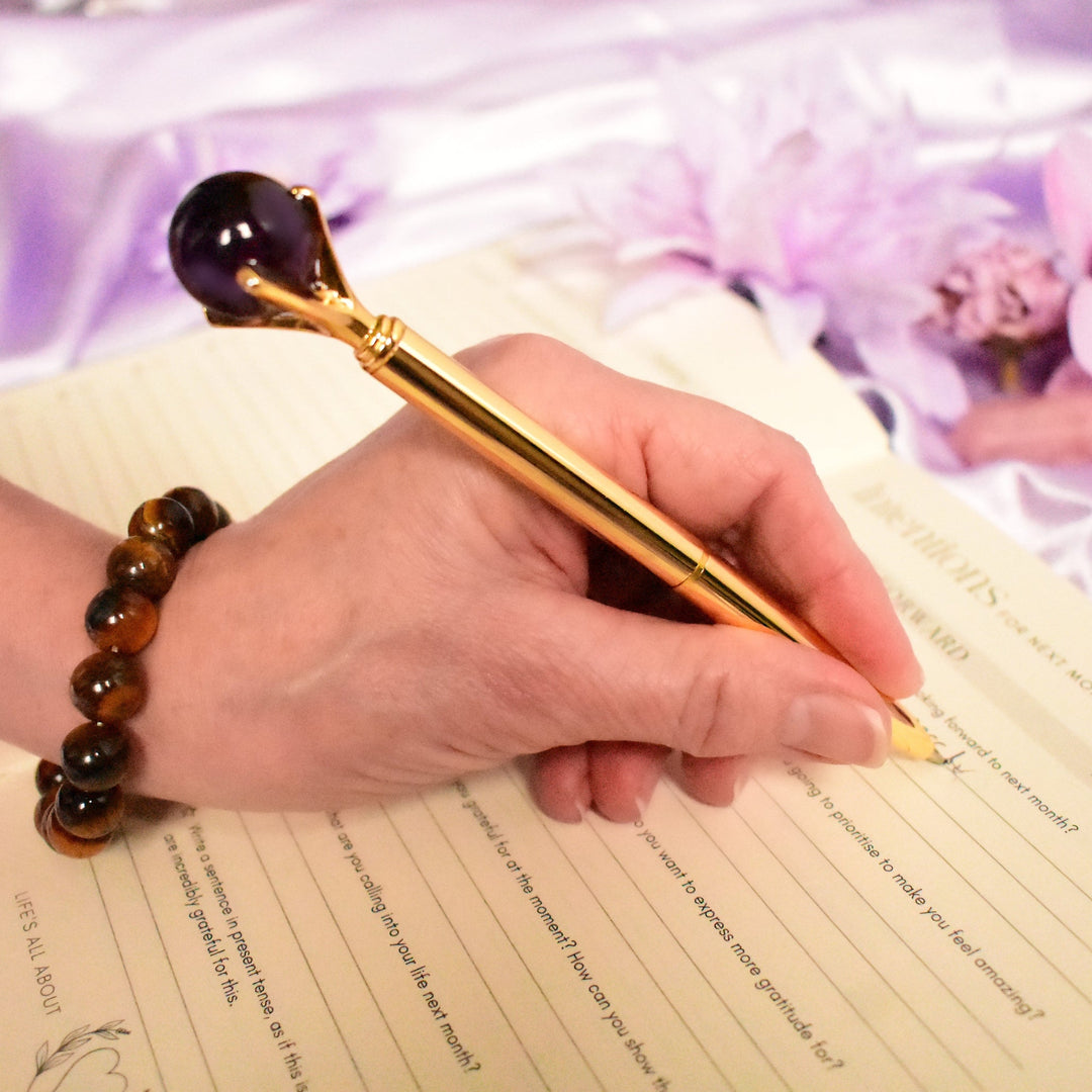 Hand holding a pen over a notebook with a decorative background